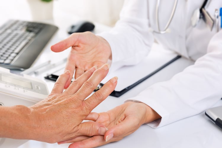 Hand einer Rheuma-Patientin in den Händen der Ärztin