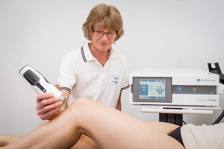 Frau Dr. Roderfeld führt eine Stoßwellentherapie am Knie einer Patientin durch